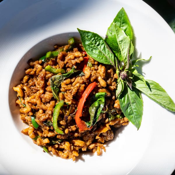 Thailicious' Thai basil chicken with green beans and red peppers, garnished with fresh basil.
