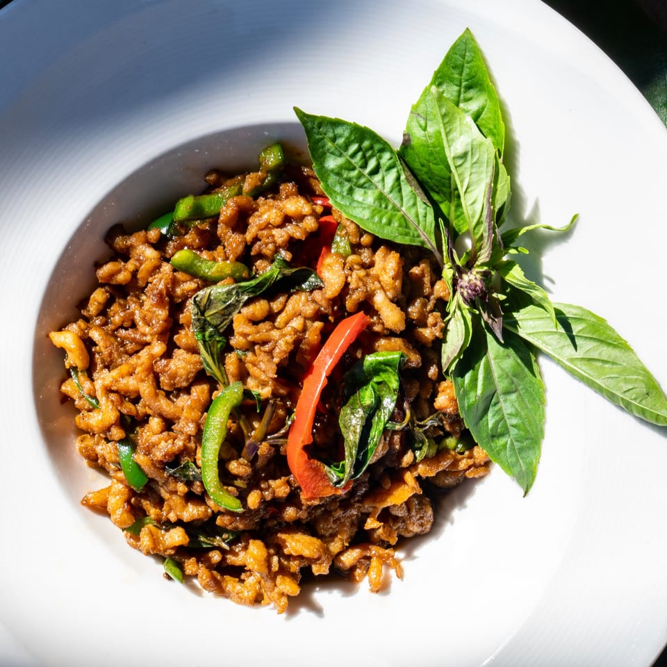 Thailicious' Thai basil chicken with green beans and red peppers, garnished with fresh basil.