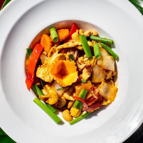 Thailicious cashew chicken stir-fry with bell peppers, onions, and green onions in a white bowl.