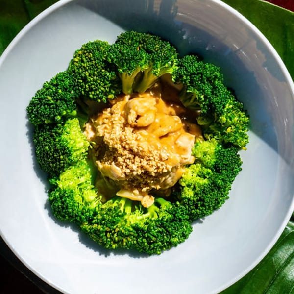 Thailicious' chicken with peanut sauce and broccoli florets, served in a white bowl.